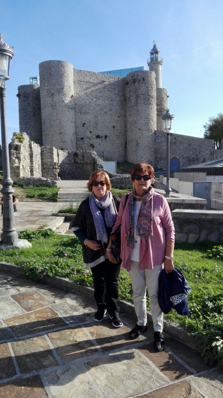 Ventura y Montse con el Castillo Faro al fondo, en Castro Urdiales.